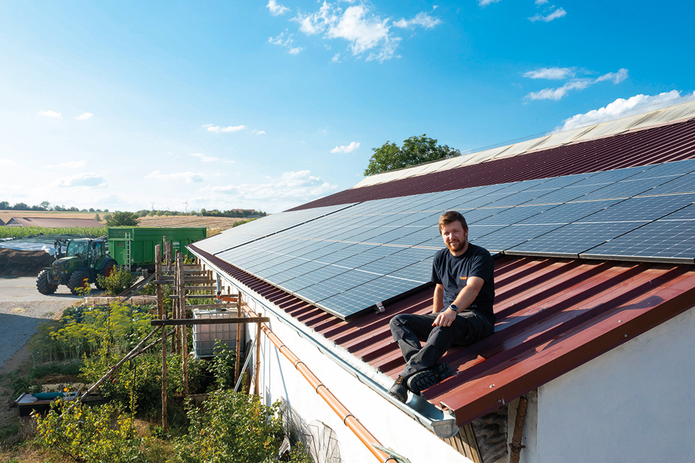 Landwirt Alexander Kuhn auf dem Dach seines Milchviehstalles. Die im Oktober 2021 installierte PV-Anlage ist die erste Solarstromanlage auf dem Hof und ein sichtbares Signal für den Generationenwechsel. (Fotos: Kostal)